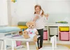 A young girl is standing next to a teddy bear on a table in a child's room. Anteprima dell’immagine prodotto