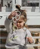 A young child is holding a toy chain of rings. Produktbild-Vorschau