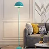 A turquoise floor lamp is shown next to a gray sofa with decorative pillows. Voir les images du produit