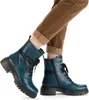 A pair of blue lace-up boots worn by a person with brown pants and tan socks. Voir les images du produit
