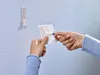 A person is shown applying adhesive strips to a wall. Anteprima dell’immagine prodotto