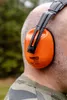 A close-up shot of a person wearing orange ear defenders. Produktbild-Vorschau