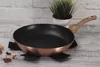A frying pan is placed on a wooden surface in front of a brick wall. Voir les images du produit