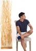 A man is sitting on a chair next to a decorative wooden screen. Náhľad obrázku produktu