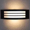 A black rectangular wall light with three white illuminated panels is mounted on a textured light gray wall. Anteprima dell’immagine prodotto