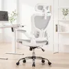 A white ergonomic office chair with gray mesh accents is shown in a well-lit room with a desk and shelves in the background. Náhled obrázku produktu