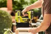 A person is using a Ryobi cordless nail gun to assemble a wooden box outdoors. Anteprima dell’immagine prodotto