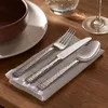 A table setting with cutlery on a napkin, a bowl, and a glass. Produktbild-Vorschau
