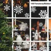 A window decorated with white snowflake stickers for Christmas, with a Christmas tree in the foreground. Produktbild-Vorschau
