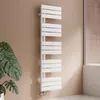 A white designer radiator is mounted on a light brown wall, with a large green plant to the left and a shower enclosure to the right. Podgląd zdjęcia produktu