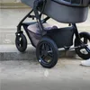 Close-up of a stroller's wheels and basket, with graphical overlays indicating features. Voir les images du produit