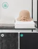 A shelf with folded towels and a hat, with close-ups of fabric textures below. Produktbild-Vorschau