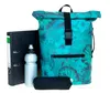 A roll-top backpack with a floral pattern, a binder, a water bottle, and a pencil case are displayed against a white background. Produktbild-Vorschau