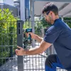 A man is using a Bosch cordless impact wrench to attach a metal fence post. Voir les images du produit