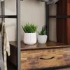 A close-up view of a wardrobe with plants on a shelf and clothes hanging. Produktbild-Vorschau