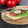 A sandwich with cheese, lettuce, tomato, and cucumber on a wooden cutting board, with tomatoes in the background. Produktbild-Vorschau