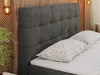 A close-up view of a dark gray upholstered headboard and pillows on a bed. Produktbild-Vorschau