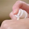 A hand is dispensing serum from a pump bottle onto the back of another hand. Anteprima dell’immagine prodotto