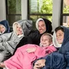 A family sitting on a couch, all wearing oversized hooded blankets. Náhled obrázku produktu