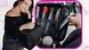 A woman is holding a black makeup case, and a hand is reaching into the open case to grab a makeup item. Náhľad obrázku produktu