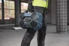 A construction worker in a high-visibility vest carries a blue Bosch radio on a construction site. Produktbild-Vorschau
