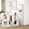A white tiered bookshelf is placed in a living room setting, next to a sofa and artwork on the wall. Náhled obrázku produktu