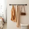 A wall-mounted coat rack with a jacket, scarf, and handbag hanging on it, next to a bed and window. Produktbild-Vorschau