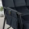 A close-up of a black velvet chair armrest with a side pocket holding a remote control. Náhled obrázku produktu