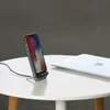 A smartphone is charging on a wireless charging stand next to a laptop on a white table. Produktbild-Vorschau