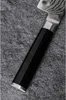 A close-up view of a knife handle and part of the blade, resting on a textured gray surface. Náhled obrázku produktu
