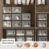 A closet interior with stacked storage boxes filled with various items, including shoes, toys, and folded clothes. Some boxes are open, showing their contents. A text overlay at the bottom left reads 'Space Saving Shoe Cabinet'. Náhľad obrázku produktu