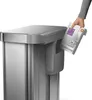 A hand is inserting a trash bag dispenser into a trash can. Podgląd zdjęcia produktu