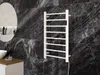 A white towel warmer is mounted on a dark marble wall in a modern bathroom. Produktbild-Vorschau