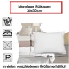 A white pillow is shown on a bed with other pillows and bedding. Produktbild-Vorschau
