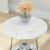 A round marble-effect side table with a vase of peach-colored flowers and a teacup on top. A small gray radio is visible on the lower shelf. Anteprima dell’immagine prodotto