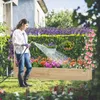 A woman is watering a raised garden bed filled with colorful flowers. The garden bed has a trellis in the background. Produktbild-Vorschau