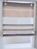 A Roman blind with horizontal stripes in various shades of brown, beige, and white, hanging in a window frame. Produktbild-Vorschau
