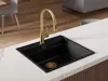 A black kitchen sink with a gold faucet on a white countertop. Produktbild-Vorschau