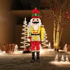 A large, illuminated nutcracker figure stands in a yard decorated with Christmas lights. Produktbild-Vorschau