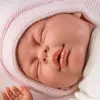 Close-up of a baby doll's face wearing a pink bonnet. Podgląd zdjęcia produktu