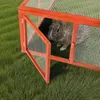A rabbit is inside a wooden hutch on a grassy lawn. Voir les images du produit