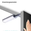 A close-up of a magnetic door latch mechanism attached to a cabinet or door frame, with a hand reaching towards a dark surface on the right. Produktbild-Vorschau