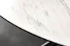 A close-up view of the edge of a round table with a white marble-like ceramic top and a black edge, resting on a dark gray surface. Produktbild-Vorschau