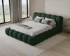 A bedroom scene with a large green upholstered bed. Voir les images du produit