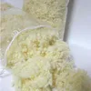 A close-up shot of loose, fluffy, cream-colored filling material, likely wool balls, spilling out of clear plastic bags. Produktbild-Vorschau