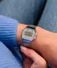 A person wearing a blue sweater and jeans, showing off a silver Casio watch on their wrist. Voir les images du produit