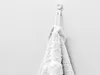 A white towel hanging on a white hook against a textured white wall. Anteprima dell’immagine prodotto
