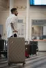 A man stands in a train station or airport with his luggage. Produktbild-Vorschau