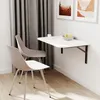 A wall-mounted folding table with two chairs in a room with curtains and artwork. Náhled obrázku produktu