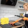 A woman is cleaning a kitchen stovetop with a steam cleaner. Podgląd zdjęcia produktu
